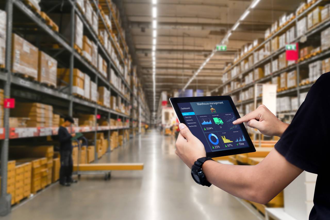 Shows a person using a tablet computer while standing in a warehouse