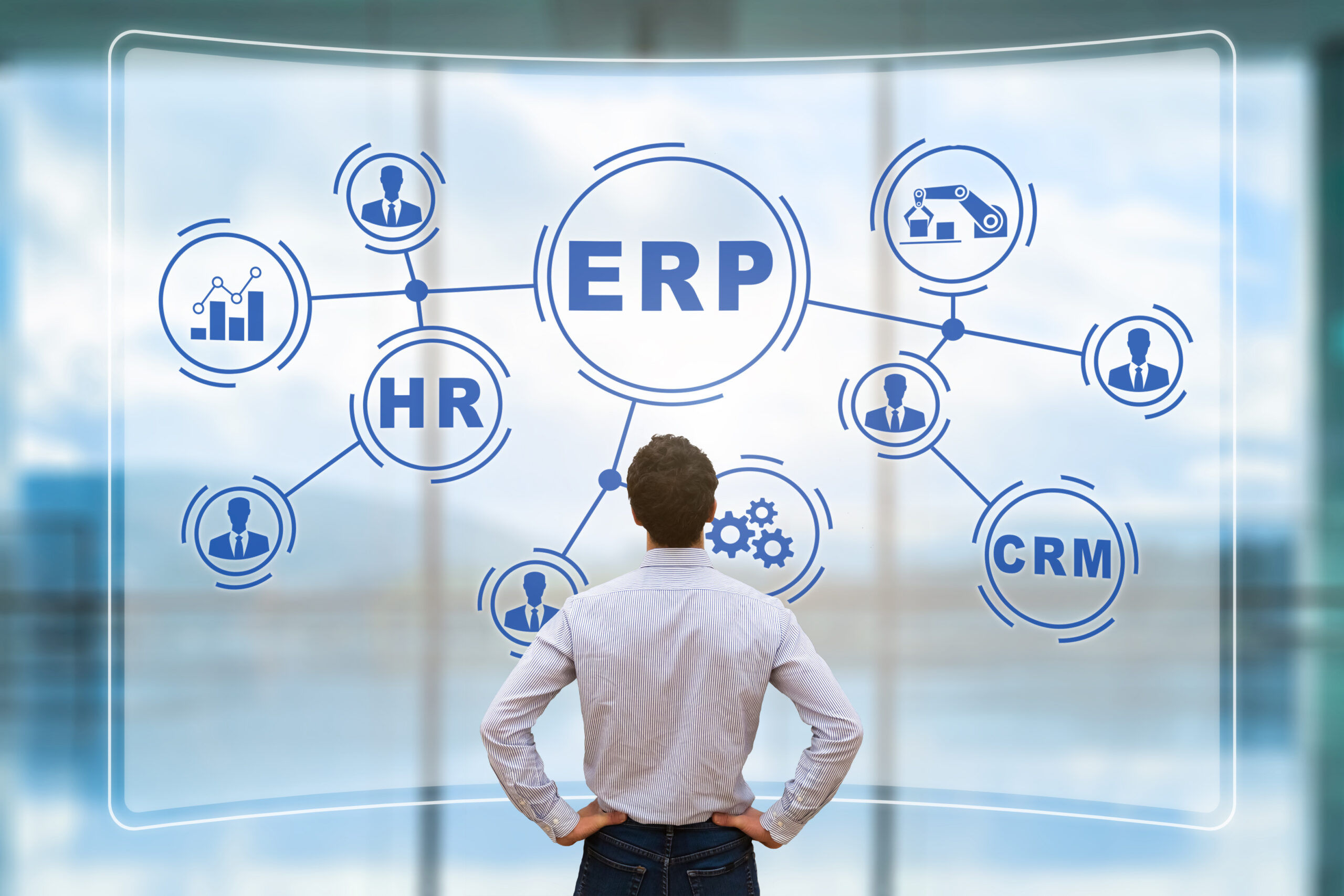 Image shows the rear view of a man looking up at a glass wall with a graphic representation of an ERP